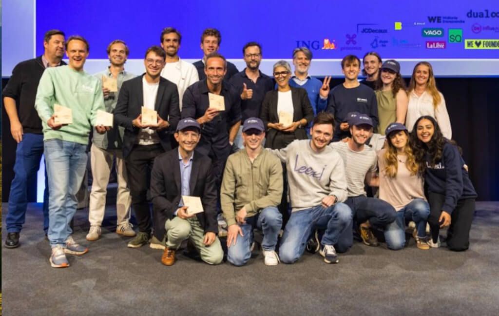 A diverse group of participants proudly poses with their awards on stage after a successful event or competition. A large group of diverse people holding small awards on a stage.
