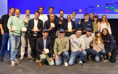This celebratory photo captures a diverse group of individuals proudly displaying their awards on a stage. Diverse group of people, some holding awards, posing happily on a stage.