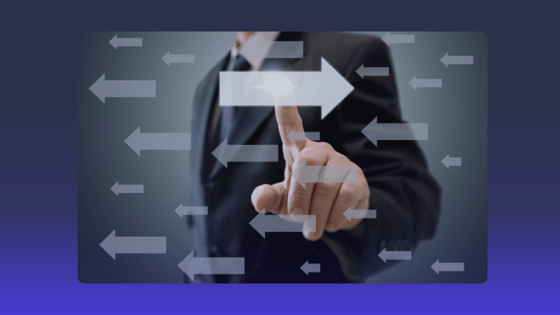 A person in a suit points at a prominent forward-pointing arrow amidst other directional arrows.