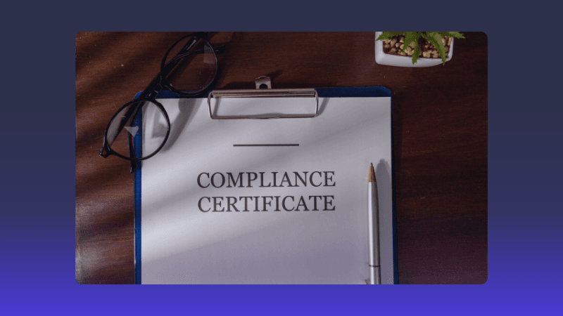 A compliance certificate document is displayed on a clipboard, emphasizing the importance of regulatory adherence. Clipboard with a document titled 'COMPLIANCE CERTIFICATE' on a wooden desk.