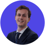 Young man in a dark suit and tie smiling against a purple background.