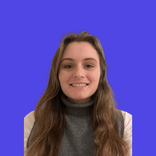 Young woman with long brown hair, smiling, wearing a grey turtleneck against a blue background.