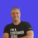 Smiling bald man with glasses, wearing a t-shirt saying 'I'M A CUSTOMER HERO'.