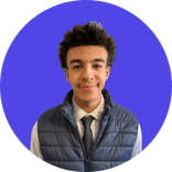 Young man with dark curly hair smiling, wearing a white shirt, tie, and blue vest.